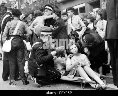 Les Beatles à Liverpool, vendredi 10 juillet 1964. Retour à l'accueil pour soirée première de "une dure journée de Nuit" à l'Odeon Cinema. Sur la photo, les filles se sentir faibles sont pris en charge à l'extérieur de l'hôtel de ville. Banque D'Images