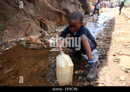 Nairobi, Kenya. 22 mai, 2015. Un garçon de l'école récupère l'eau stagnante près de ligne de chemin de fer à Kibera où le choléra a été rapporté à Nairobi, Kenya, le 22 mai 2015. Les techniciens médicaux de Kenya national du comté et les gouvernements ont décidé de mettre fin à la récente flambée de choléra dans le pays dans les 30 jours. Les cas de choléra ont été signalées dans 11 comtés du Kenya, laissant 65 morts, depuis le début de janvier. © John Okoyo/Xinhua/Alamy Live News Banque D'Images