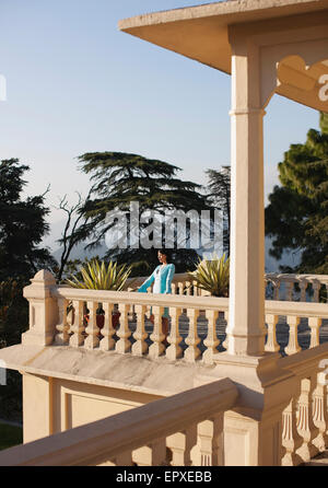 Une jeune femme se tient sur le balcon à l'extérieur de la suite vice-royal à Ananda dans l'Himalaya, Le Palais Estate, Narendra Nagar. Banque D'Images