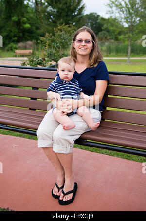 La mère et le fils assis sur un banc de parc à un parc extérieur aire de jeux Banque D'Images