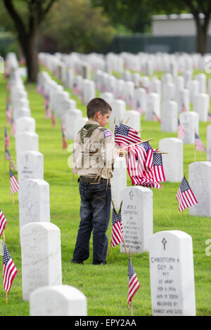 Un scout lieux de sépulture à des drapeaux américains pendant les préparatifs du Memorial Day au Fort Sam Houston National Cemetery Banque D'Images