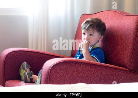 Garçon assis sur une chaise et regarder la télévision Banque D'Images