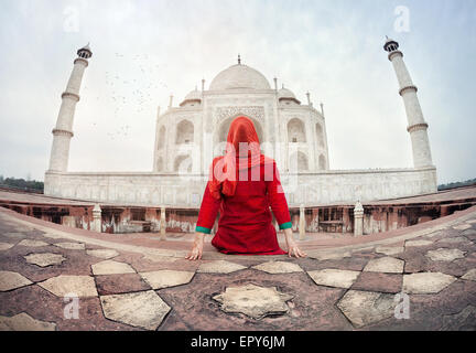 Femme en costume rouge assis sur le plancher et à la recherche au Taj Mahal à Agra, Uttar Pradesh, Inde Banque D'Images