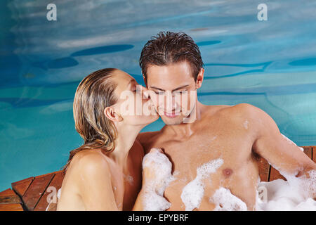 Happy woman kissing man in whirlpool dans leurs vacances en spa Banque D'Images