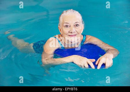 Vieille Femme natation dans l'eau avec piscine dans un hôtel kickboard Banque D'Images