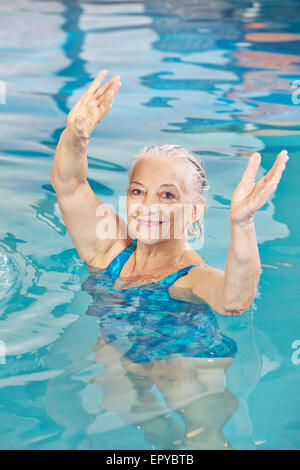Les bras de levage femme senior dans aqua fitness class dans une piscine Banque D'Images