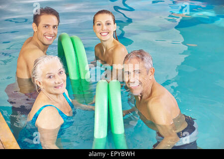 Deux couples heureux dans aqua fitness class dans une piscine avec des nouilles Banque D'Images