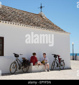 Les cyclistes prendre du repos à l'extérieur d'une ancienne chapelle en s'appuyant sur l'Algarve Portugal Banque D'Images