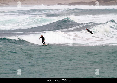 L'ANSE DE SENNEN, Cornwall, Angleterre - 22 octobre 2014 : Surfers attraper une vague lors d'une froide journée d'automne, le 22 octobre 2014 dans Sennen Co Banque D'Images