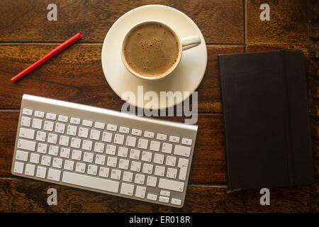 Clavier d'ordinateur, tasse de café, un ordinateur portable et crayon rouge sur la table en vieux bois foncé. Banque D'Images