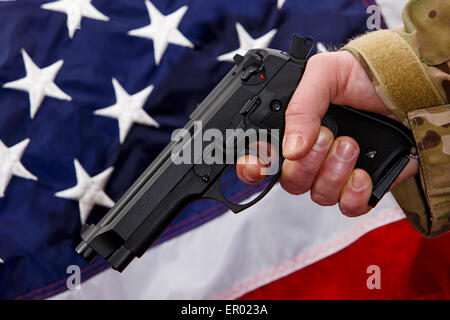 L'homme en treillis de poing Beretta holding avec le doigt sur la détente en face de drapeau des États-Unis d'Amérique Banque D'Images