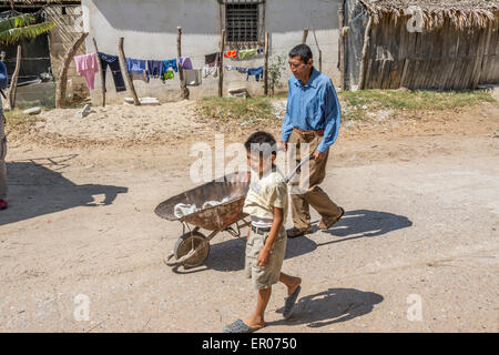 Man pushing wheelbarrow avec jeune garçon marchant à côté au Guatemala Banque D'Images