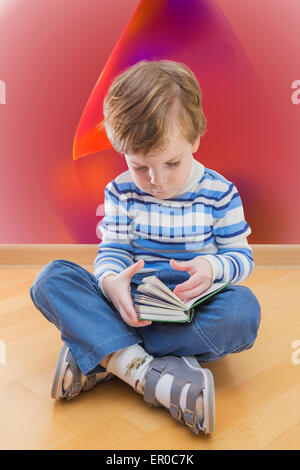 Boy reading book coin sur le sol et red abstract background Banque D'Images