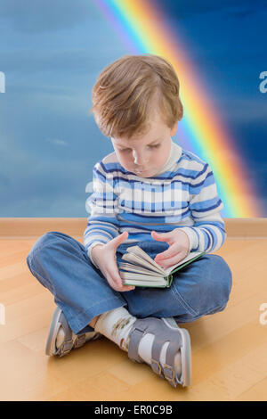 Boy reading book coin sur le sol et arc-en arrière-plan Banque D'Images