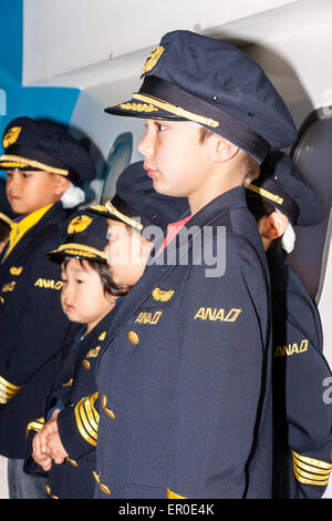 Centre d'activités pour enfants, Kidzania, à Nishinomiya, Japon. Intérieur. Une rangée d'enfants habillés comme capitaines de compagnie aérienne avec un enfant caucasien en premier plan. Banque D'Images