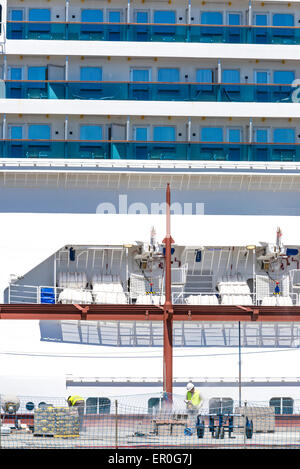 Les travailleurs de la construction réparation du dock avec une croisière de luxe moderne à l'arrière-plan dans le port de Barcelone, Catalogne, Espagne Banque D'Images