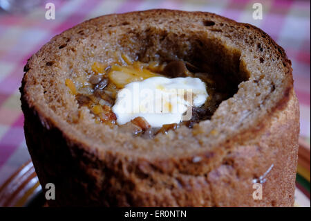 Un plat classique de soupe aux champignons lituaniens servi chaud dans un pain de seigle creusé, avec une cuillère de crème sure sur le dessus. Lituanie Banque D'Images