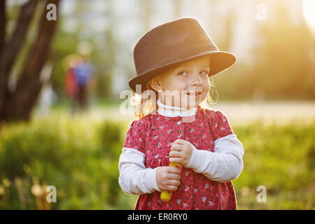 Funny cute little Girl with a hat gâtés, portrait en extérieur au printemps. Le concept d'une enfance heureuse. Banque D'Images