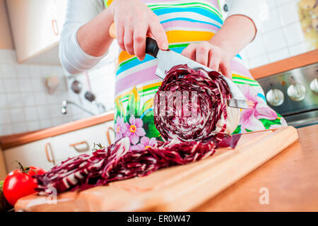 Woman's hands cutting chou rouge, derrière les légumes frais. Banque D'Images