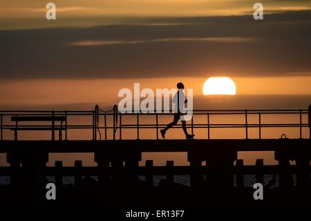 Météo France : Pays de Galles Aberystwyth UK Dimanche 24 Mai 2015 Un homme solo jogge en silhouette contre le soleil couchant sur la baie de Cardigan à la veille de la maison de banque mai lundi d'Aberystwyth, sur la côte ouest du pays de Galles Crédit photo : Keith morris / Alamy Live News Banque D'Images