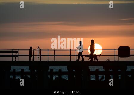 Météo France : Pays de Galles Aberystwyth UK Dimanche 24 Mai 2015 - par une chaude soirée ensoleillée deux personnes marcher leur chien sont silhouette sur le coucher de soleil sur la baie de Cardigan à la veille de la maison de banque mai lundi d'Aberystwyth, sur la côte ouest du pays de Galles Crédit photo : Keith morris / Alamy Live News Banque D'Images