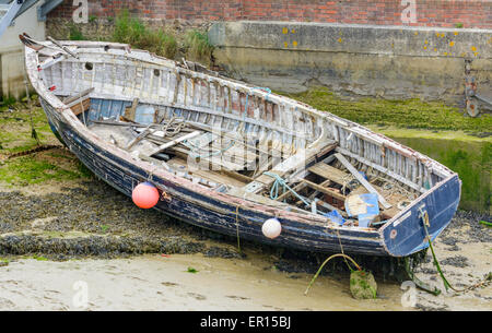 Une grande barque en bois sur la boue sur le côté de la rivière, à marée basse. Banque D'Images