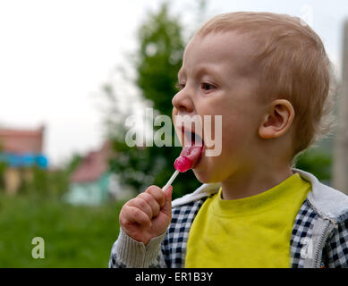 Little Boy eating candy , l'extérieur Banque D'Images