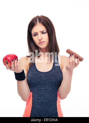 Sports femme faisant choix entre Apple en bonne santé et en mauvaise santé le chocolat isolé sur un fond blanc. Banque D'Images