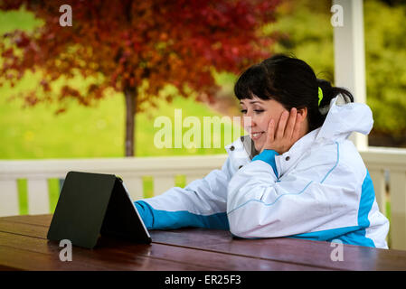 Les femmes à la fin des années vingt, assis avec une tablette dans l'Arbor en bois au cours de la journée d'automne pluvieuse Banque D'Images