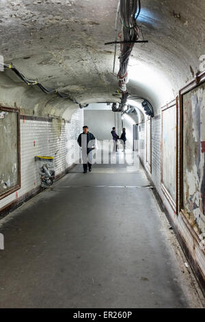 Homme marchant dans métro métro délabré avec de vieilles affiches et de passage des câbles électriques, Paris Banque D'Images