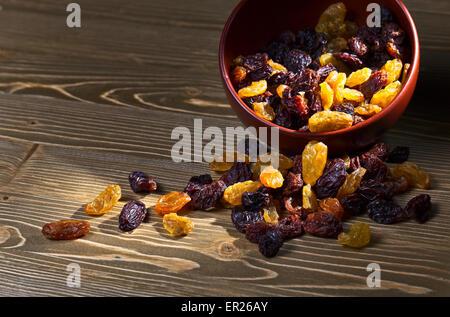Les raisins secs dans un brown dich on wooden table Banque D'Images