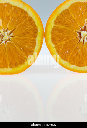 Deux moitiés d'une orange sur le fond dégradé blanc et gris avec les réflexions de orange sur le fond. Prises de photos haute résolution Banque D'Images