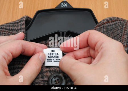 Woman's hands holding clothes label. 3X. 3 exrta grande. Fabriqués en Chine. Banque D'Images