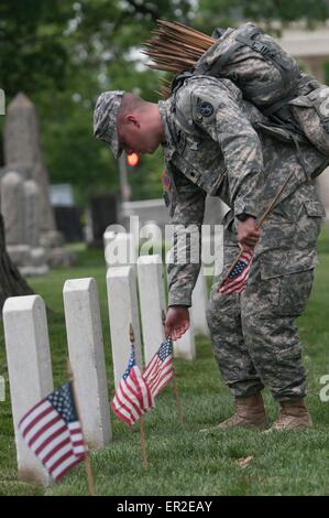 Un soldat de l'Armée américaine à partir de la vieille garde places drapeaux devant des lieux de sépulture en l'honneur du Jour du Souvenir au Cimetière National d'Arlington, le 21 mai 2015 à Arlington, en Virginie. La vieille garde a mené dans des pavillons, quand un drapeau américain est placé à chaque pierre tombale, depuis 1948. Banque D'Images