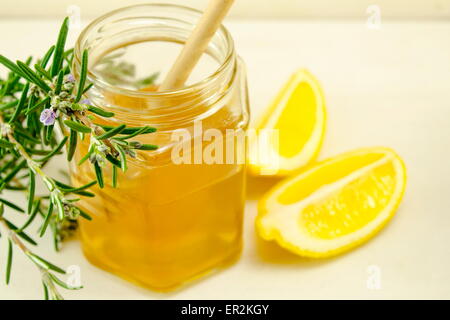 Pot de miel d'une cuillère de bois et les citrons sur une table Banque D'Images