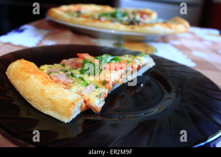 Morceau de pizza savoureuse avec farce appétissante sur la plaque Banque D'Images