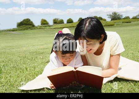 Mère et fille japonaise en lisant un livre dans un parc de la ville Banque D'Images