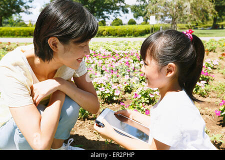 Mère et fille japonaise avec le comprimé dans un parc de la ville Banque D'Images