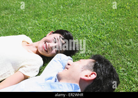 Heureux couple japonais portant sur l'herbe dans un parc Banque D'Images