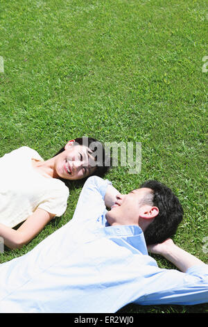 Heureux couple japonais portant sur l'herbe dans un parc Banque D'Images