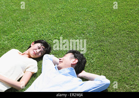 Heureux couple japonais portant sur l'herbe dans un parc Banque D'Images