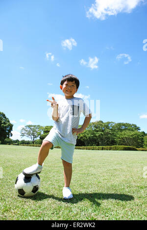 Jeune garçon japonais joue au soccer dans un parc de la ville Banque D'Images