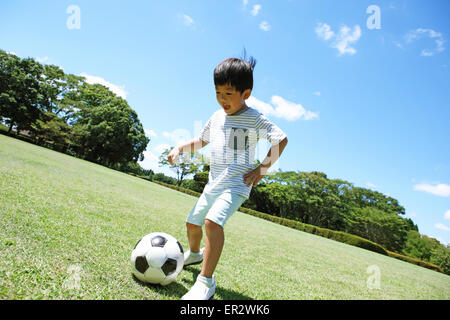 Jeune garçon japonais joue au soccer dans un parc de la ville Banque D'Images