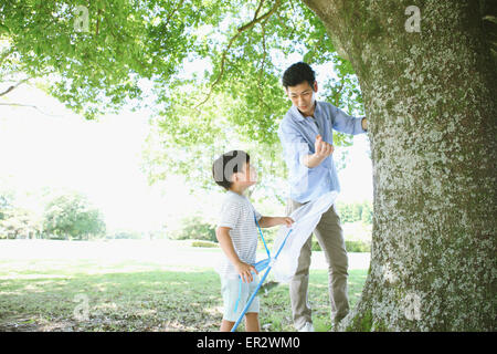 Heureux père japonais et son fils attraper des insectes dans un parc de la ville Banque D'Images