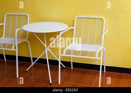 Chaise en métal blanc et bureau avec mur jaune Banque D'Images