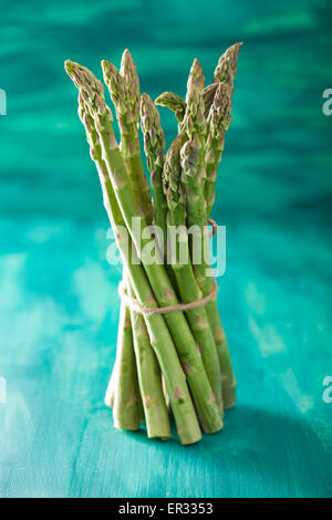 Bande d'asperges fraîches sur fond bleu turquoise Banque D'Images