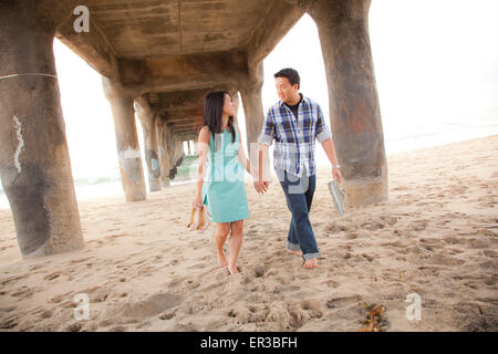 Couple Holding Hands, marche pieds nus sous une jetée Banque D'Images