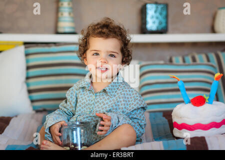 Smiling girl sitting on le lit avec un bocal de bonbons Banque D'Images