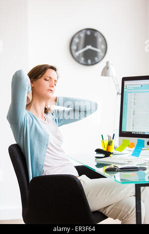 Femme souffrant de douleur au cou dans le bureau. Banque D'Images