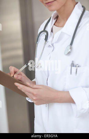 Médecin écrit le dossier du patient, cropped Banque D'Images